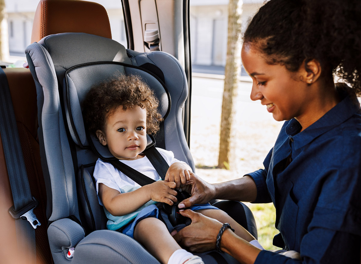 Mother securing a child in a car seat